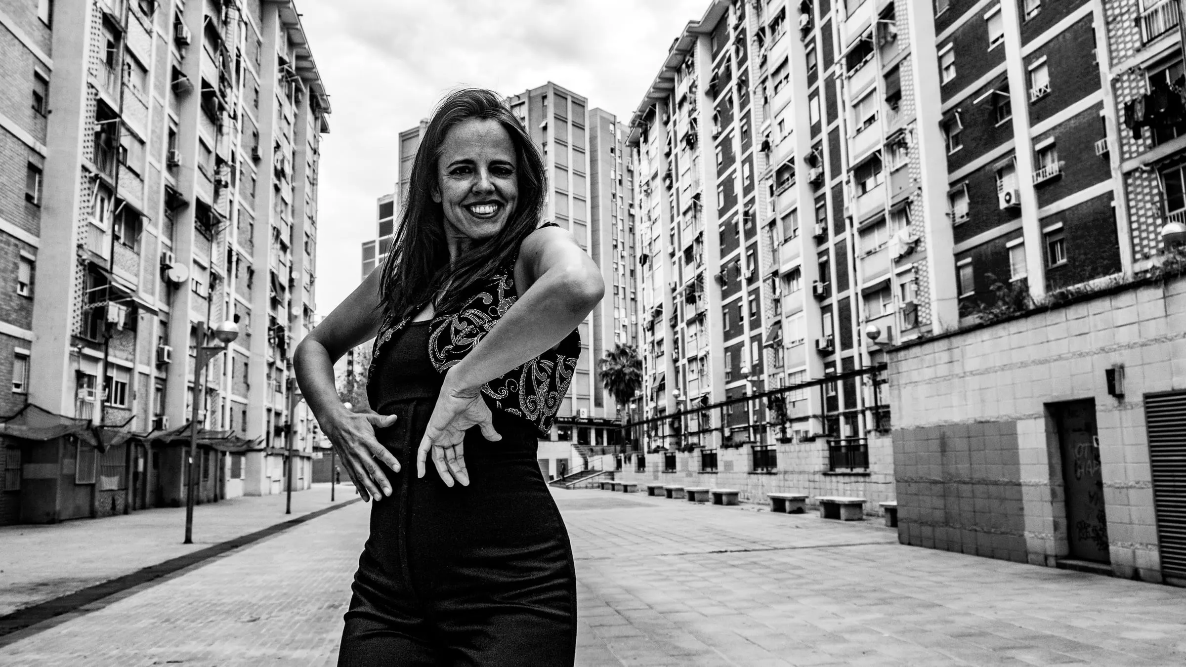 Aina Núñez baila en una calle vacía entre bloques de viviendas, con los brazos abiertos.