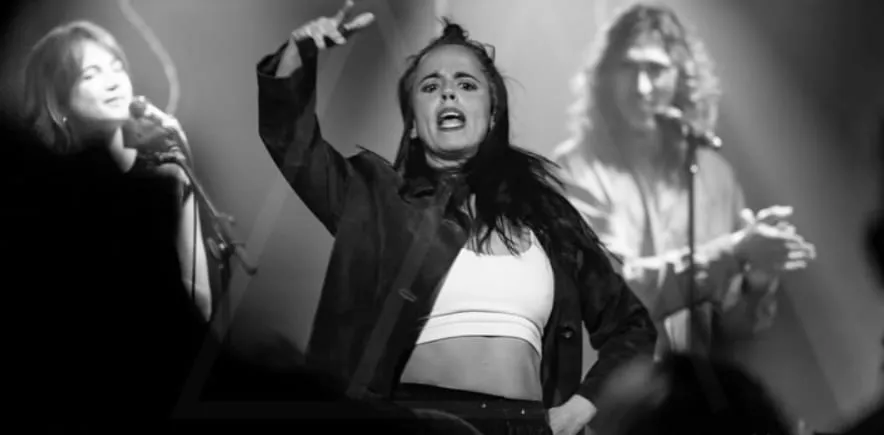 Aina Núñez baila con el brazo en alto en un concierto, entre la voz y la guitarra.