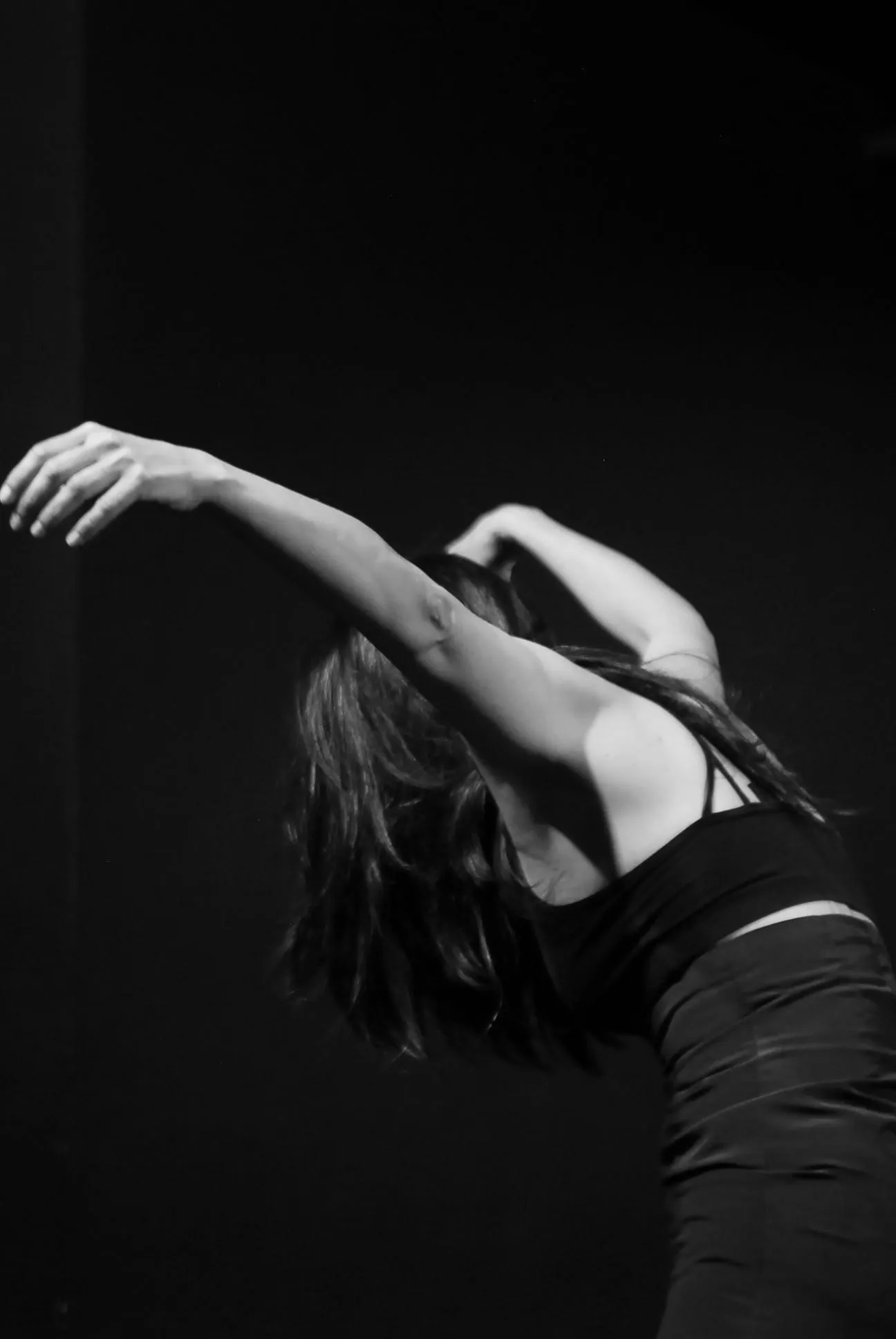 Aina Núñez arquea el torso con los brazos extendidos sobre un fondo negro.