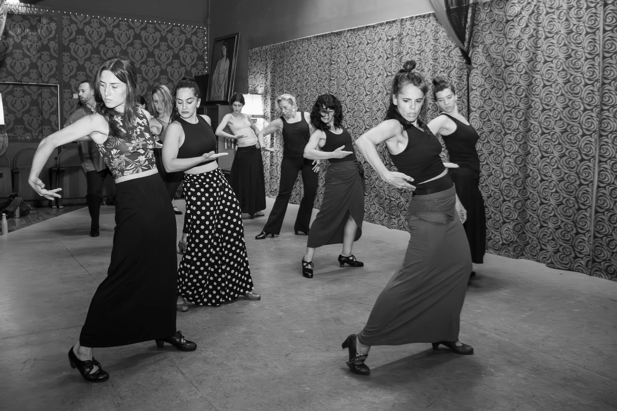 Un grupo de alumnas marca a la vez un paso de flamenco, con las faldas en movimiento.