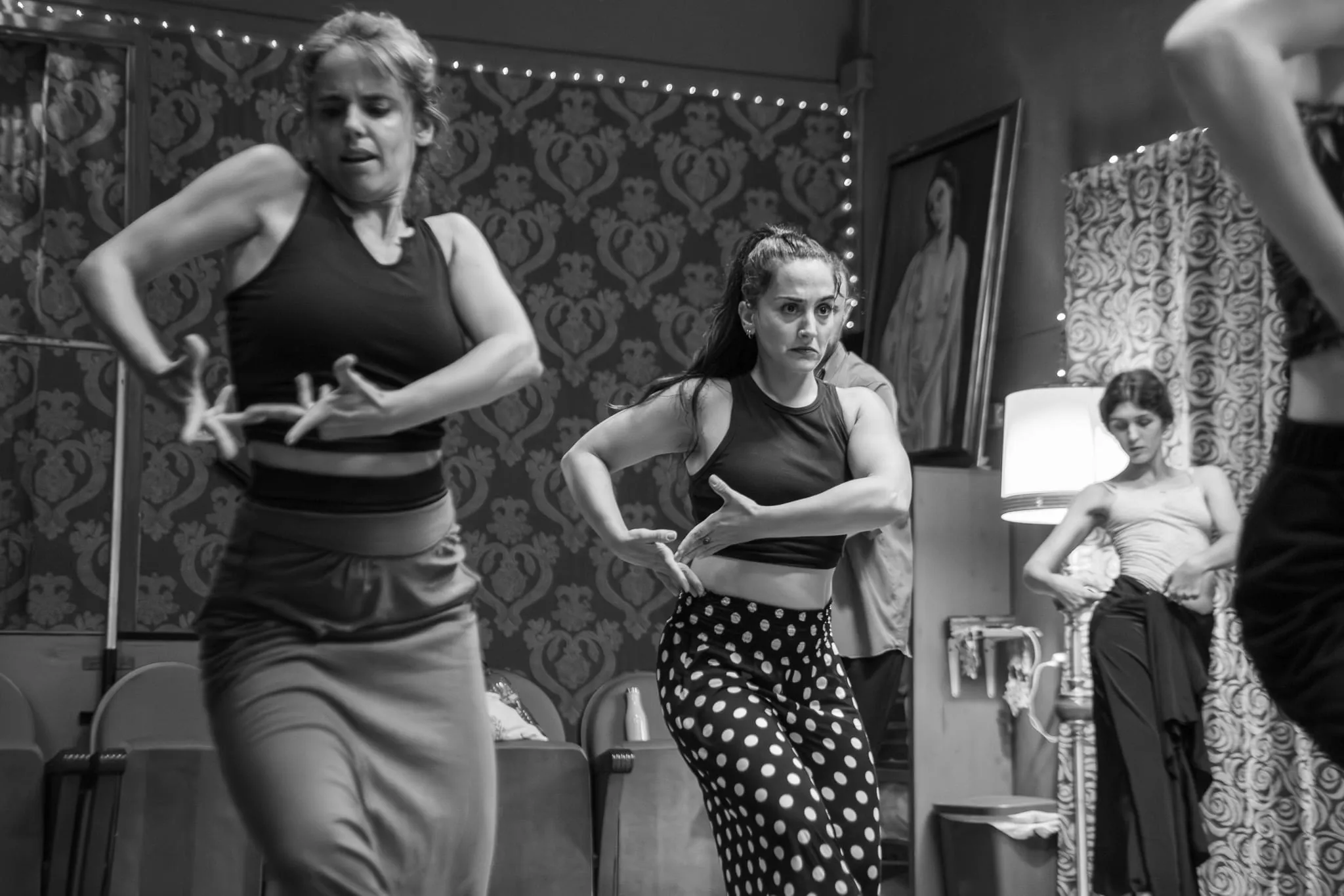 Dos alumnas marcan un paso de flamenco en el estudio, con las manos a la altura de la cintura.